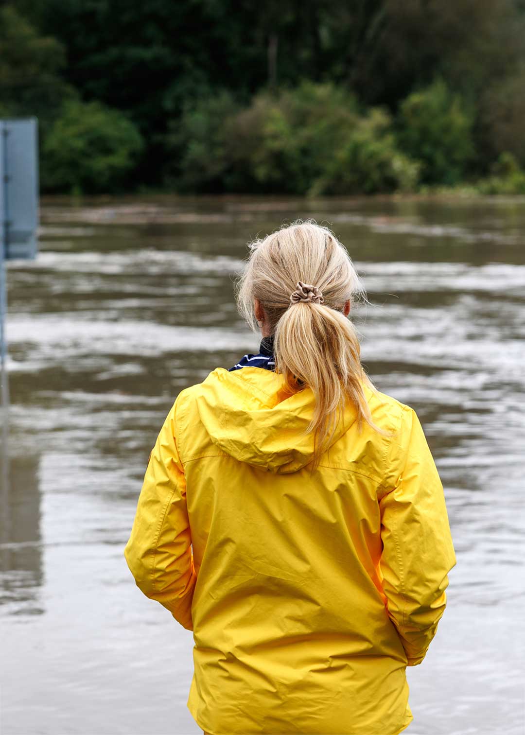 Person in yellow raincoat overlooking flood zone